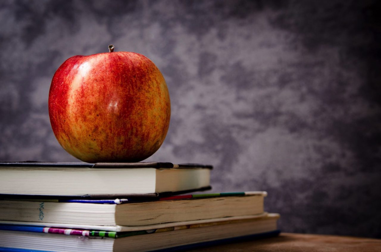 apple sitting on pile of books