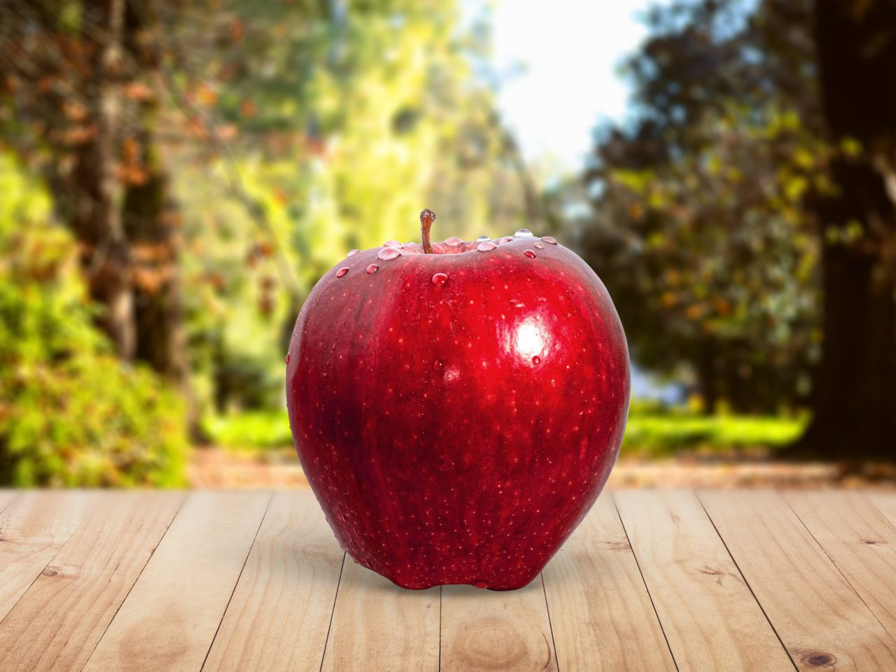 Red apple sitting on wooden picnic table